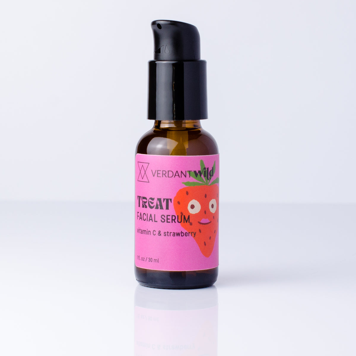 A small amber glass pump bottle of Verdant Wild Treat vitamin C Facial Serum with a black pump and a bright pink label featuring a cartoon strawberry, set against a clean white background with a soft reflection.