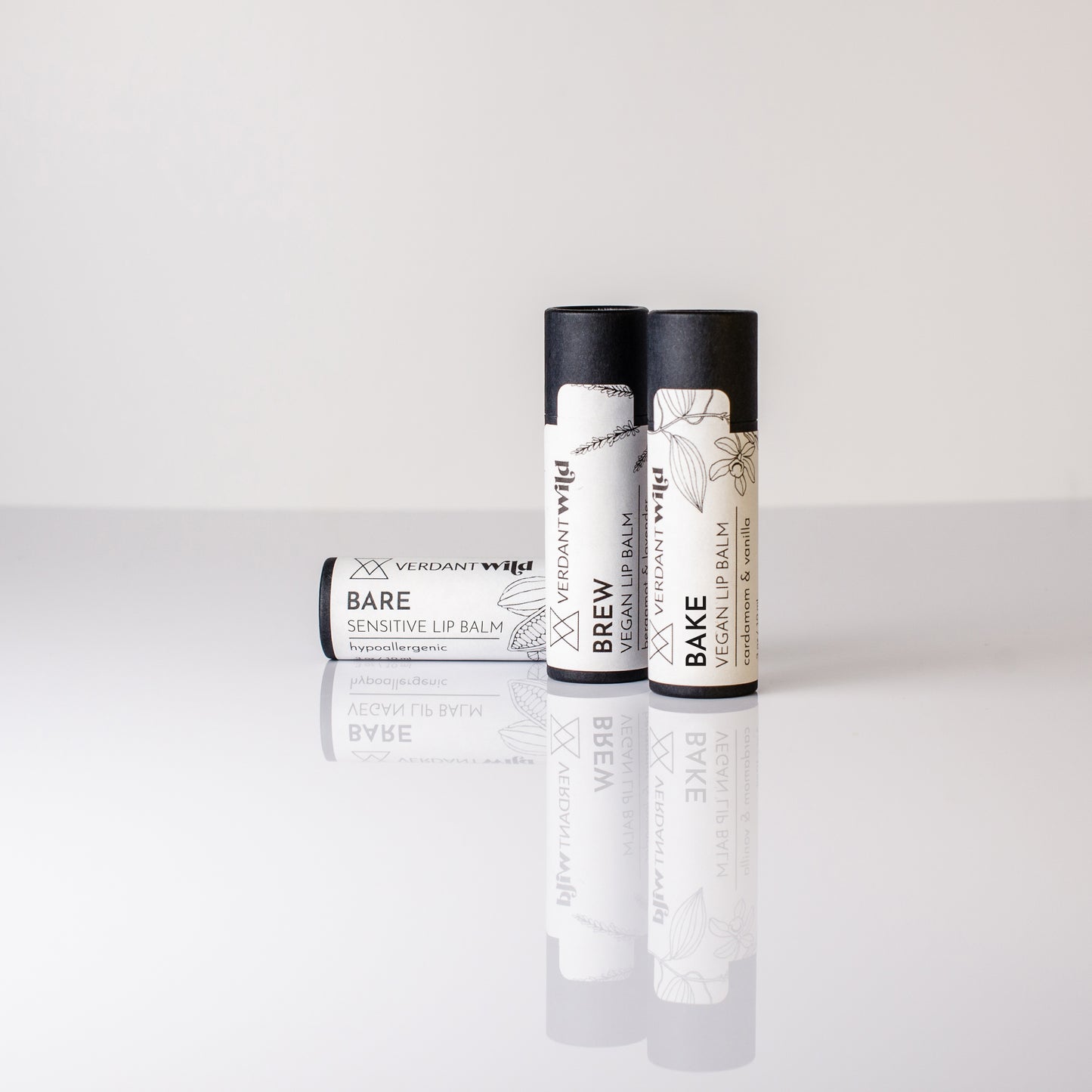 Three lip balm tubes with black lids on a white background