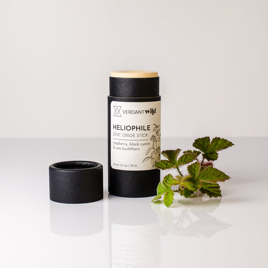 Vermont Wild Heliophile Zinc Oxide Stick on a white background with a small plant.